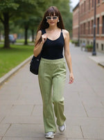 Woman with long brown hair in sunglasses and black tank wears 98degreenorth’s Flared Bootcut Fleece Sweatpants outside.