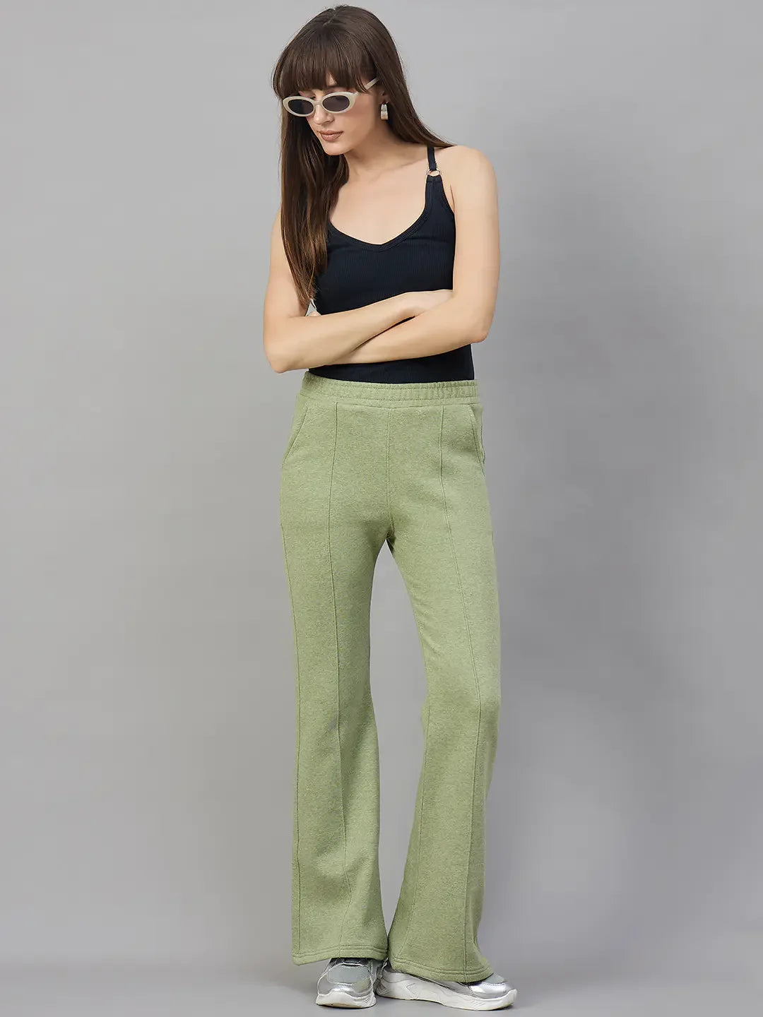 Woman in 98degreenorth Pista Melange flared bootcut fleece sweatpants, black sleeveless top, white sunglasses, silver sneakers.