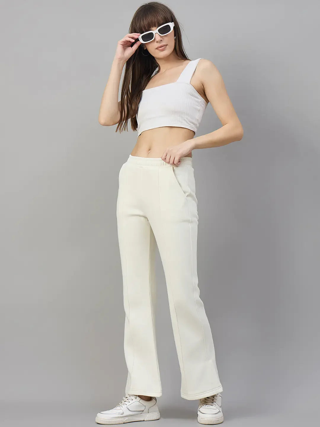 Cheerful fashion: Woman models 98degreenorth Butter Yellow Flared Sweatpants—soft lounge fleece—against gray background.