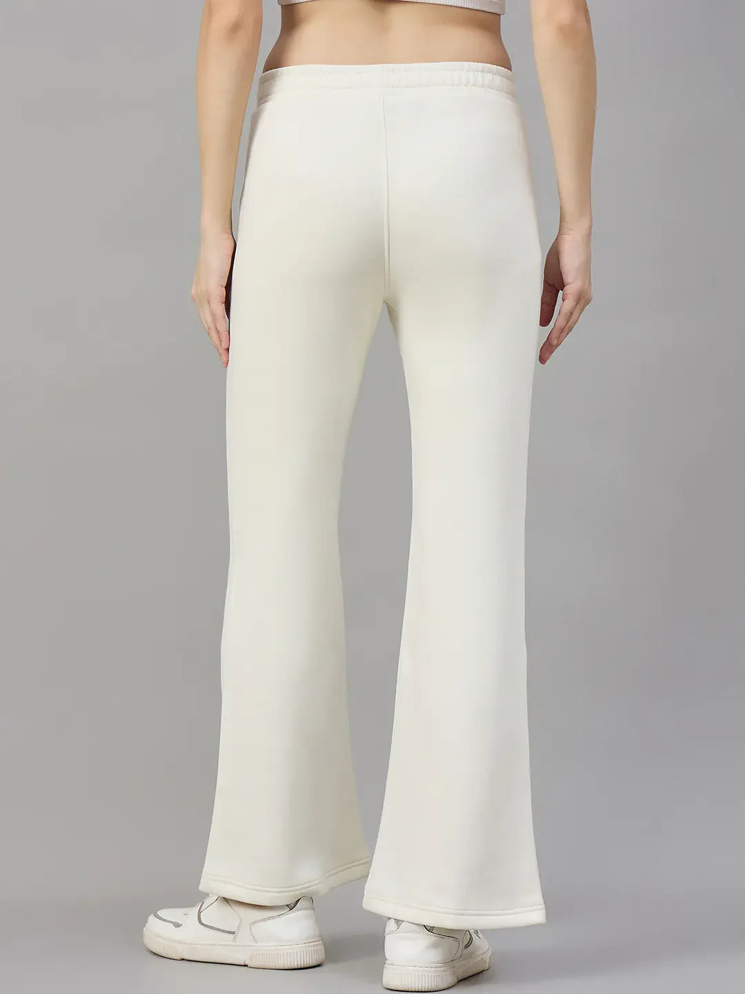 A woman in 98degreenorth Butter Yellow Flared Sweatpants, seen from the back, stands out cheerfully against gray.