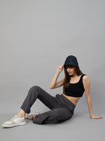 Woman in 98degreenorth Women’s Flared Sweatpants in Charcoal Grey touches her black bucket hat while sitting.
