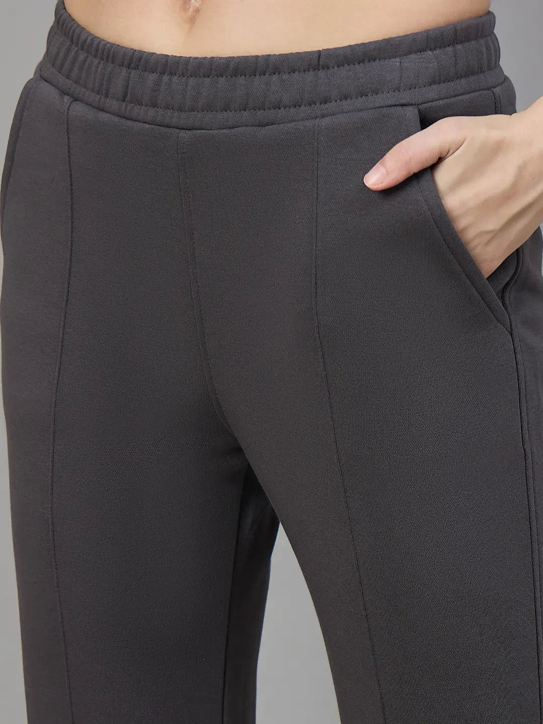 Model wearing 98degreenorth Women’s Flared Sweatpants in Charcoal Grey, hand in pocket, waist to mid-thigh view.
