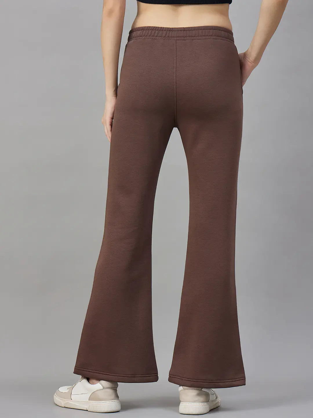 A person wears 98degreenorth Womens Flared Sweatpants in Cocoa Brown, facing away against a gray background.