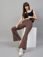 Woman in a black crop top and 98degreenorth Women’s Flared Sweatpants in Cocoa Brown sits on a white block.