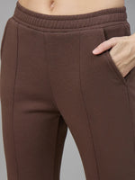 Model wears 98degreenorth Women’s Flared Sweatpants in Cocoa Brown, right hand in pocket, waist to mid-thigh view.