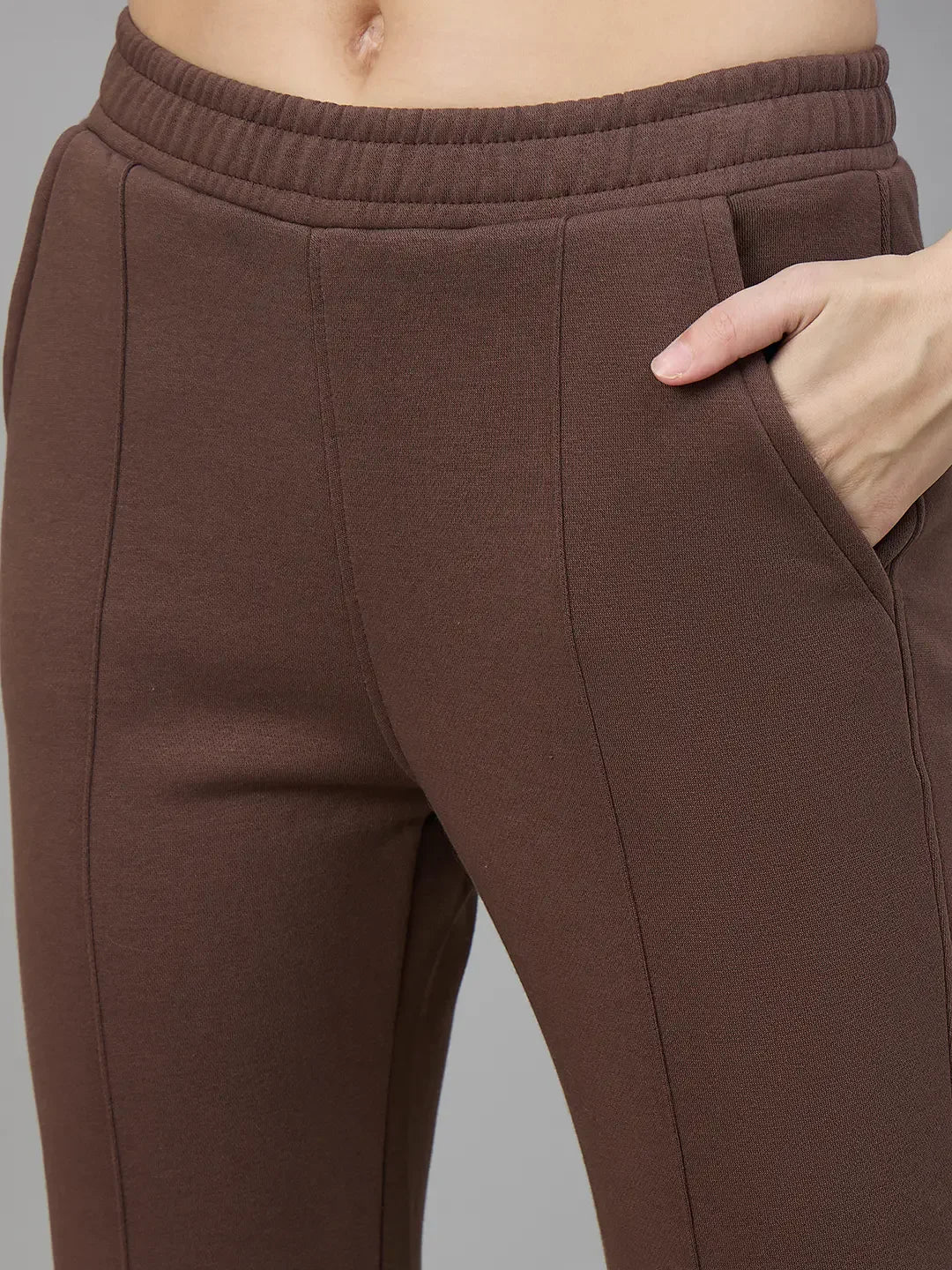 Model wears 98degreenorth Women’s Flared Sweatpants in Cocoa Brown, right hand in pocket, waist to mid-thigh view.