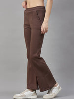 A woman wears 98degreenorth’s Cocoa Brown Flared Sweatpants and white sneakers, standing against a gray background.