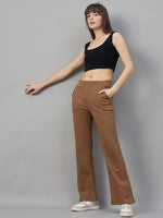 Woman in 98degreenorth Women’s Flared Sweatpants in Coffee Melange stands with a hand in pocket, wearing white sneakers.