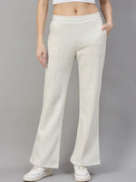 Model wears 98degreenorth Womens Flared Sweatpants in Ecru Off White with white sneakers and a crop top, on gray backdrop.