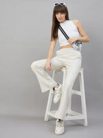Woman in 98degreenorth Women’s Flared Sweatpants in Ecru Off White sits on a wooden ladder, sneakers and sunglasses on.