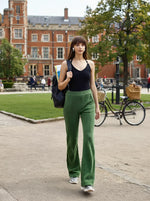 A woman in 98degreenorth Women’s Flared Sweatpants in Hunter Green walks outside by a historic brick building.