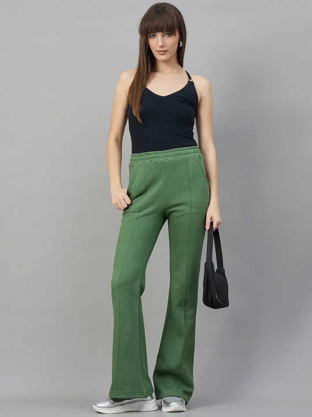 Model wears 98degreenorth Women’s Flared Sweatpants in Hunter Green, styled with a black tank and bag.