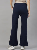 Model in 98degreenorth Women’s Flared Sweatpants in Navy Melange, shown from the back with white sneakers.
