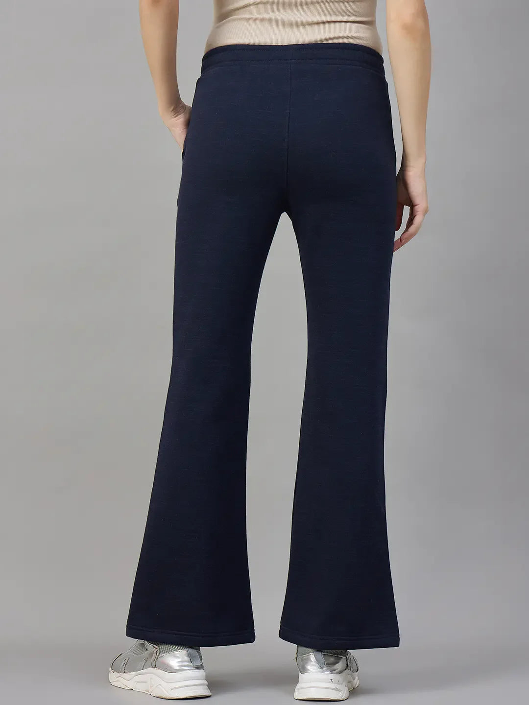 Model in 98degreenorth Women’s Flared Sweatpants in Navy Melange, shown from the back with white sneakers.