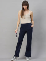 Woman wearing 98degreenorth Women’s Flared Sweatpants in Navy Melange, holding sunglasses against a gray background.