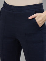 A person wears 98degreenorth Women’s Flared Sweatpants in Navy Melange, hand in pocket, waist down view.