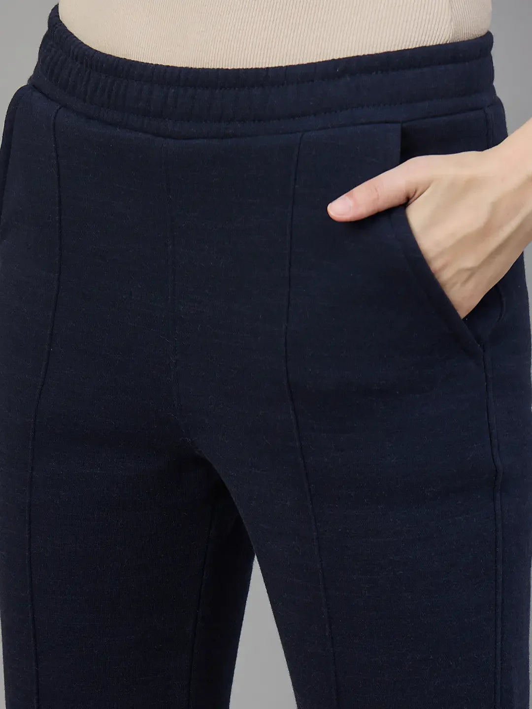A person wears 98degreenorth Women’s Flared Sweatpants in Navy Melange, hand in pocket, waist down view.