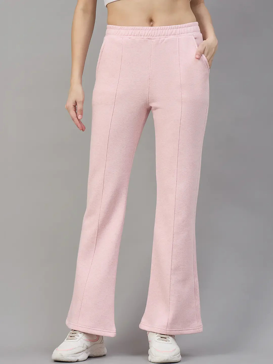 Model in 98degreenorth Women’s Flared Sweatpants in Pink Melange, styled with a crop top and white sneakers.