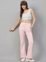 Woman in 98degreenorth Pink Melange Flared Sweatpants poses in white crop top, sneakers, and sunglasses.