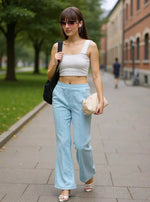 Woman in 98degreenorth Sky Melange Flared Sweatpants and sunglasses walks on sidewalk holding a bag.