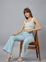 Woman wears 98degreenorth Women’s Flared Sweatpants in Sky Melange with a white crop top, seated against a gray backdrop.