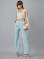 Woman in 98degreenorth Women’s Flared Sweatpants in Sky Melange, paired with a white crop top and beige clutch.