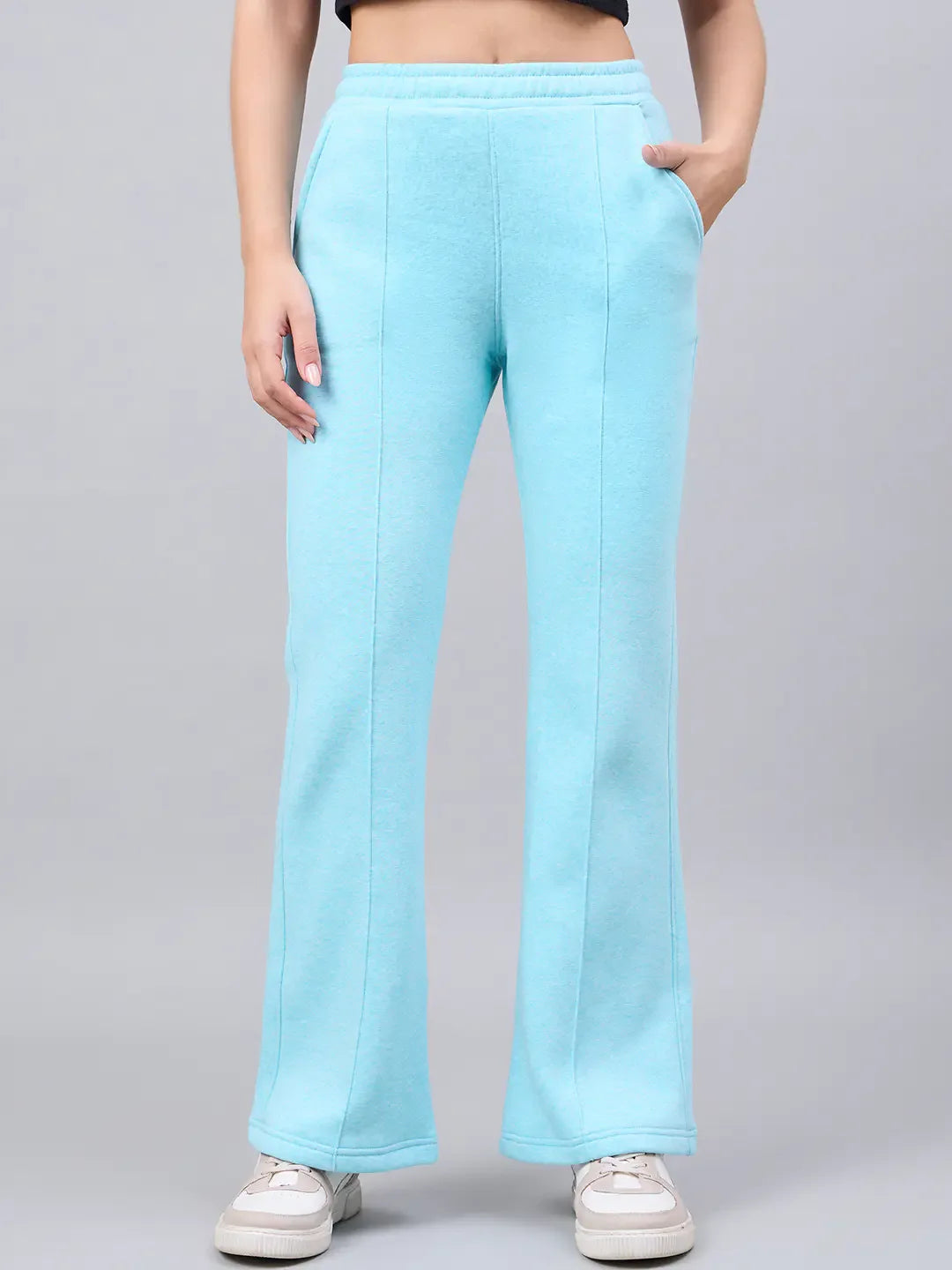 Woman in 98degreenorth turquoise blue flared sweatpants, styled with white sneakers for winter streetwear.