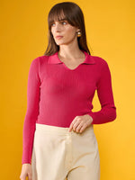 Woman in a 98degreenorth fuchsia pink ribbed collar sweater and cream pants stands against a bright yellow background.