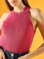 Woman in 98degreenorth’s fuchsia ribbed halter neck sleeveless knit top poses against a yellow background.
