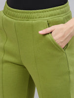 A woman wears 98degreenorth green flared bootcut sweatpants with side slit, hand in pocket, waist to mid-thigh shown.