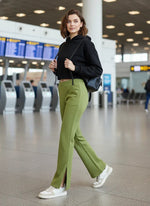 Woman in 98degreenorth Women’s Green Flared Bootcut Sweatpants with side slit walks through an airport terminal.