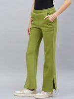 Woman in 98degreenorth green flared bootcut sweatpants with side slit, styled with white sneakers and hand in pocket.