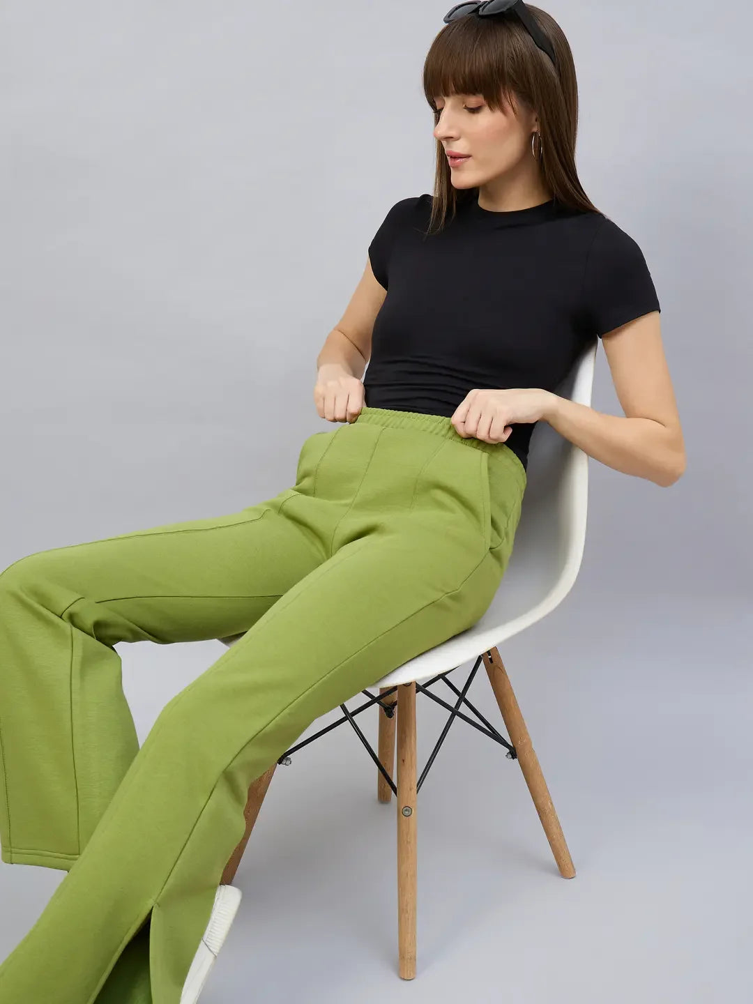 A woman adjusts her waistband in 98degreenorth Women’s Green Flared Bootcut Sweatpants with side slit.