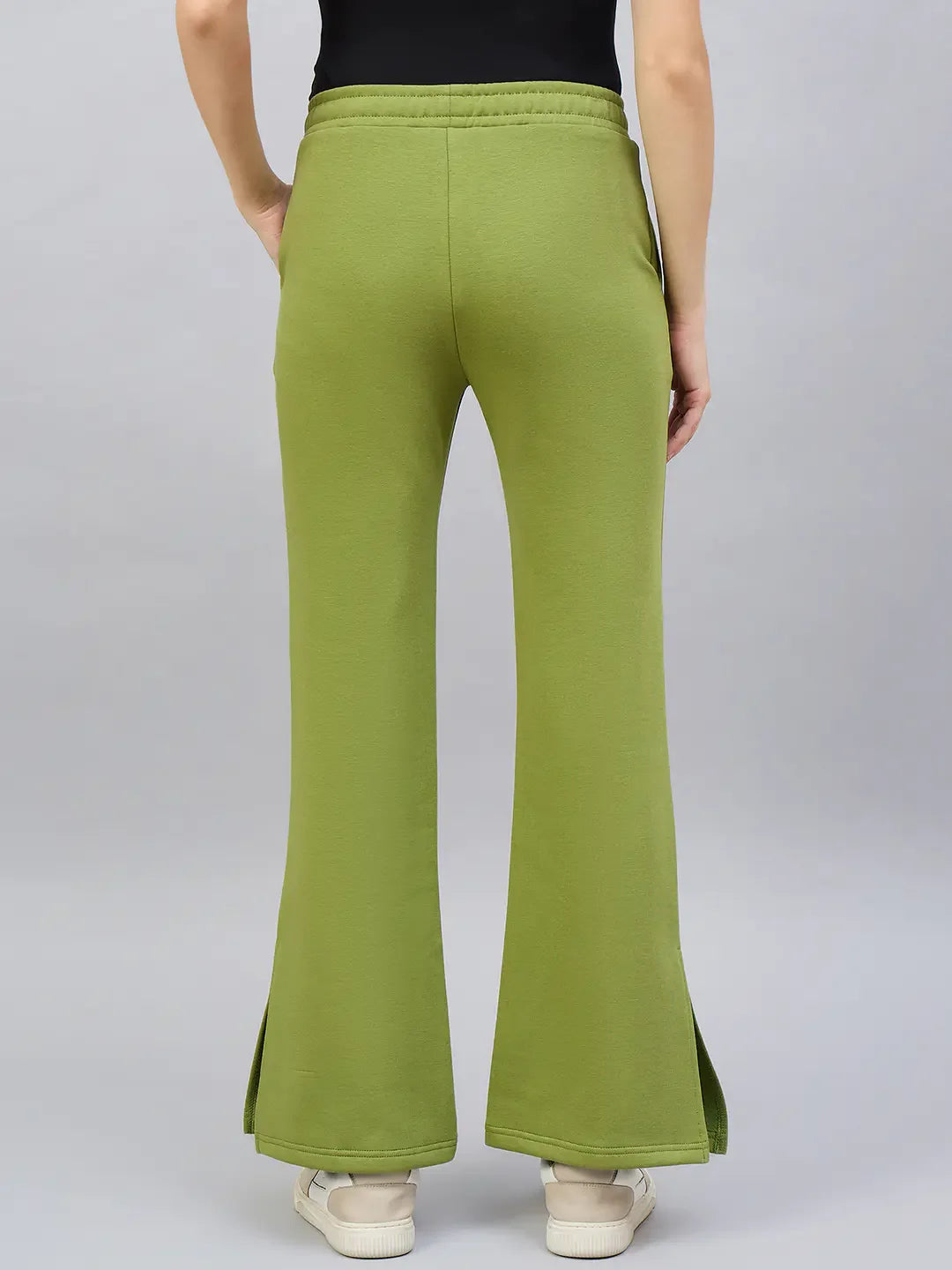 Person in 98degreenorth Women’s Green Flared Bootcut Sweatpants with side slits, black top, and white sneakers, back view.