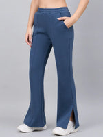 Model wears 98degreenorth Women’s Indigo Blue Bootcut Sweatpants with side slits, styled with white shoes, gray backdrop.