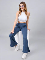 Woman in a white crop top and 98degreenorth Women’s Indigo Blue Bootcut Sweatpants sits on a white block.