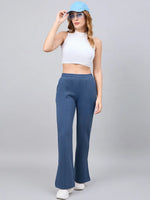Woman in a white crop top and 98degreenorth Indigo Blue Bootcut Sweatpants poses against a plain gray background.