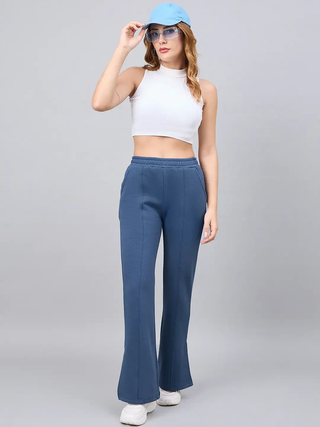 Woman in a white crop top and 98degreenorth Indigo Blue Bootcut Sweatpants poses against a plain gray background.