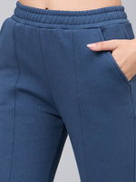 Model in 98degreenorth indigo blue bootcut sweatpants with hand in pocket, showing waistband and flared side-slit style.