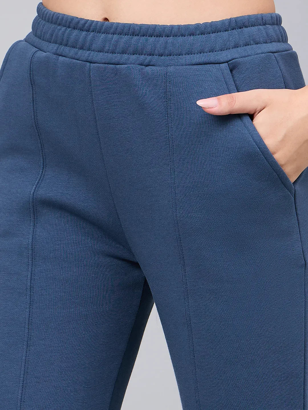 Model in 98degreenorth indigo blue bootcut sweatpants with hand in pocket, showing waistband and flared side-slit style.