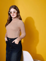 Woman in a 98degreenorth light camel high turtle-neck sweater poses against a yellow background wearing white sunglasses.