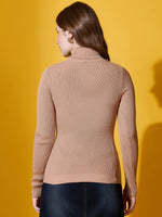 A woman wears a 98degreenorth light camel high turtle-neck sweater against a yellow background.