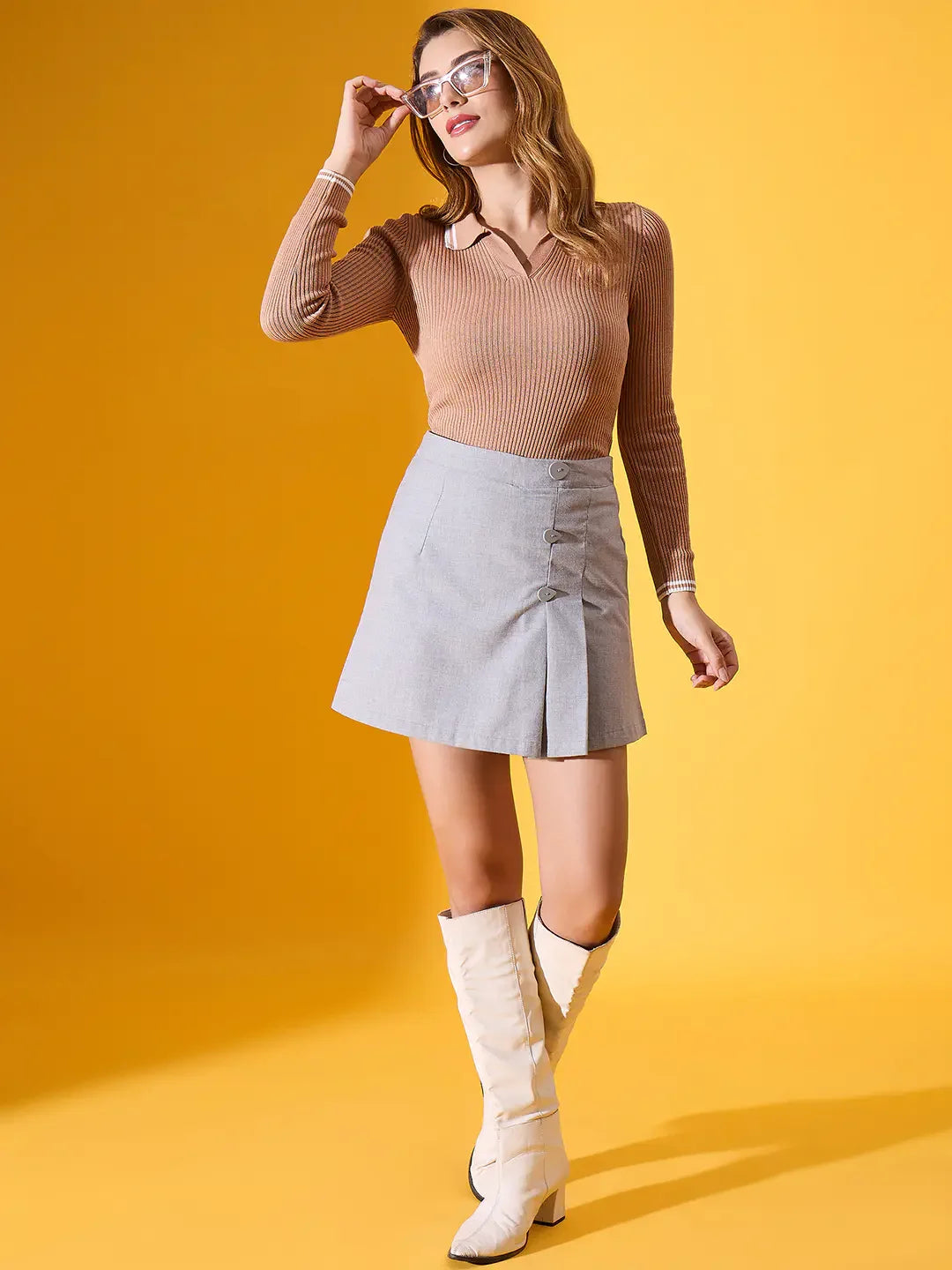 Woman in 98degreenorth’s Light Camel Ribbed Collared Sweater poses in trans-seasonal style against yellow.