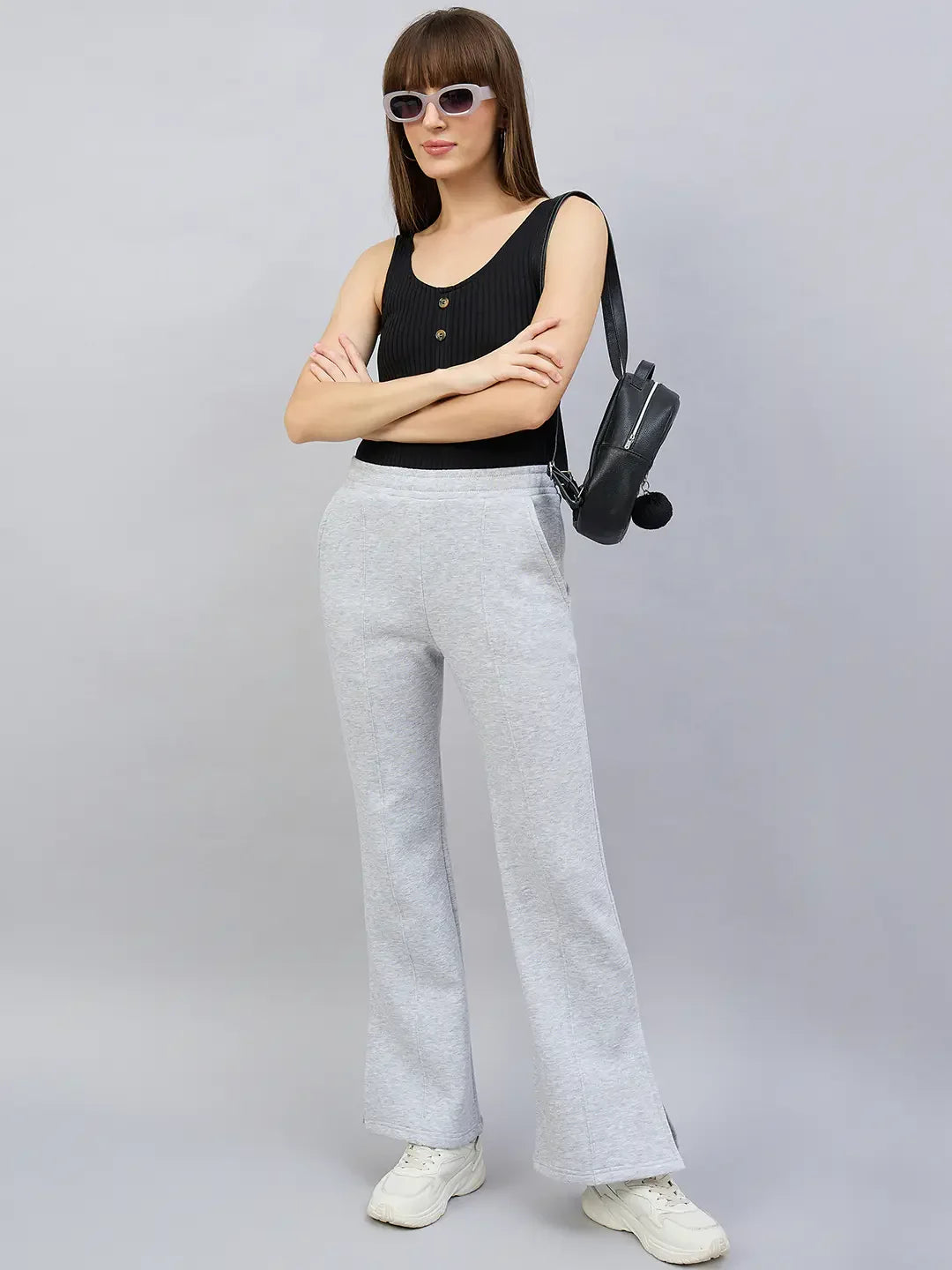 Woman in sunglasses, black sleeveless top, 98degreenorth light grey bootcut sweatpants, and a black shoulder bag.