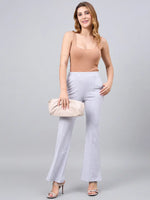 Woman in a tan tank top wears 98degreenorth light grey flared bootcut cotton stretch trousers, smiling.