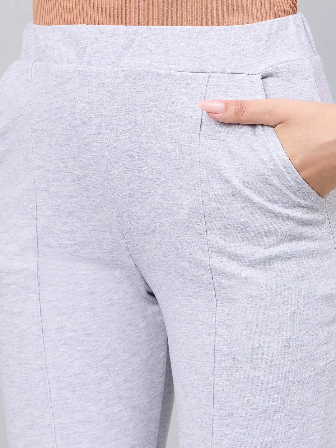 A woman models 98degreenorth’s light grey flared bootcut cotton stretch trousers, pictured waist down, hand in pocket.