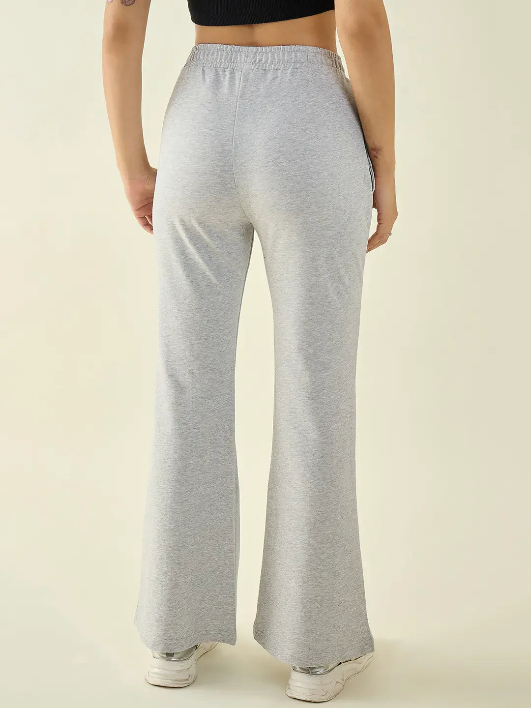Person wears 98degreenorth Women’s Light Grey Flared Fit Bootcut Pants with a black crop top and white sneakers, back facing.