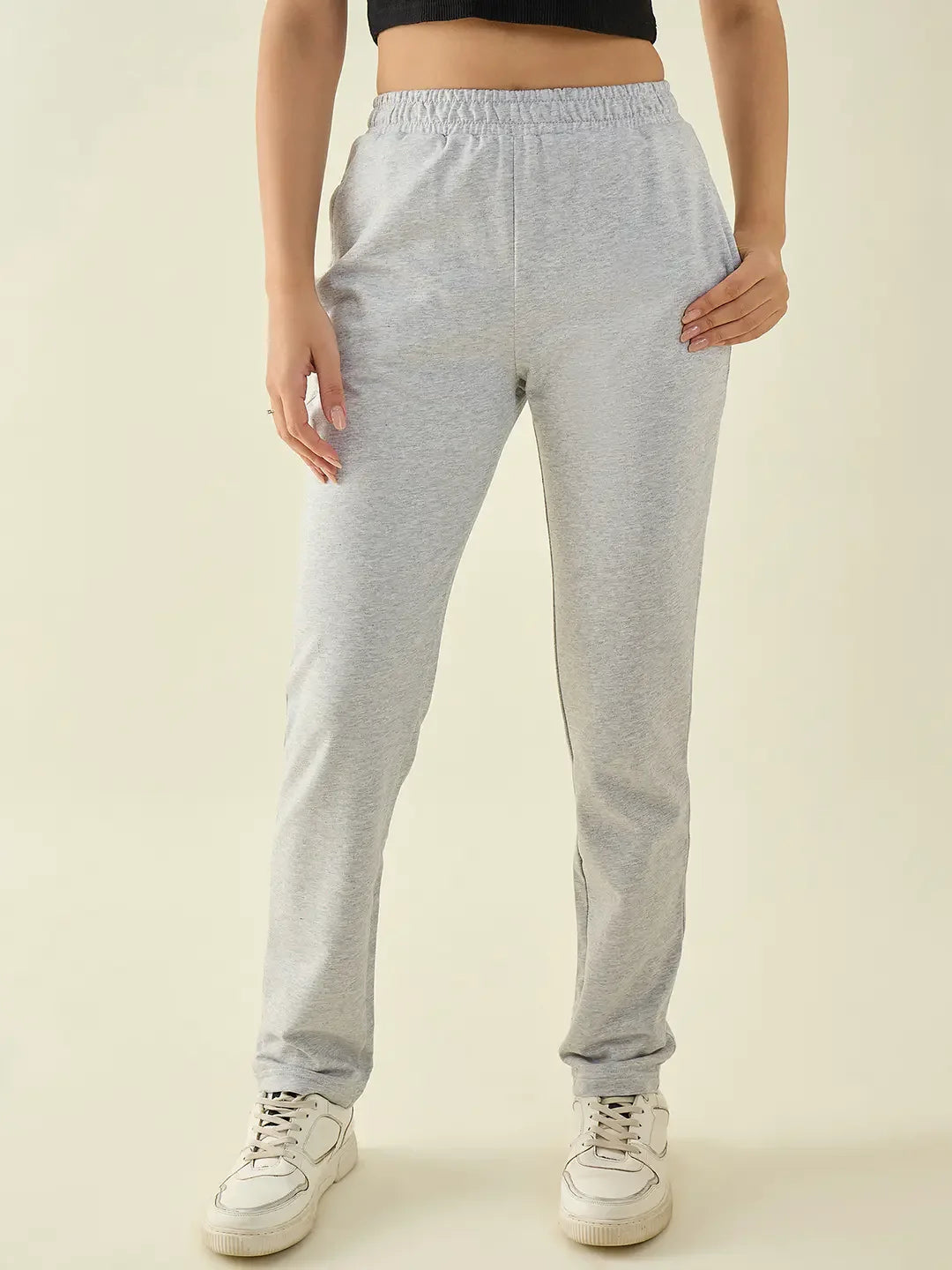 Model wears 98degreenorth Women’s Light Grey Cotton Stretchable Trousers with white sneakers and a black top.