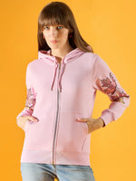 Woman in a 98degreenorth light pink fleece hoodie with leaf embroidery, posing confidently against a yellow background.
