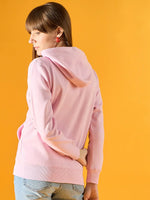 Woman wears 98degreenorth light pink fleece zipper hoodie with leaf embroidery, facing away by a yellow backdrop.